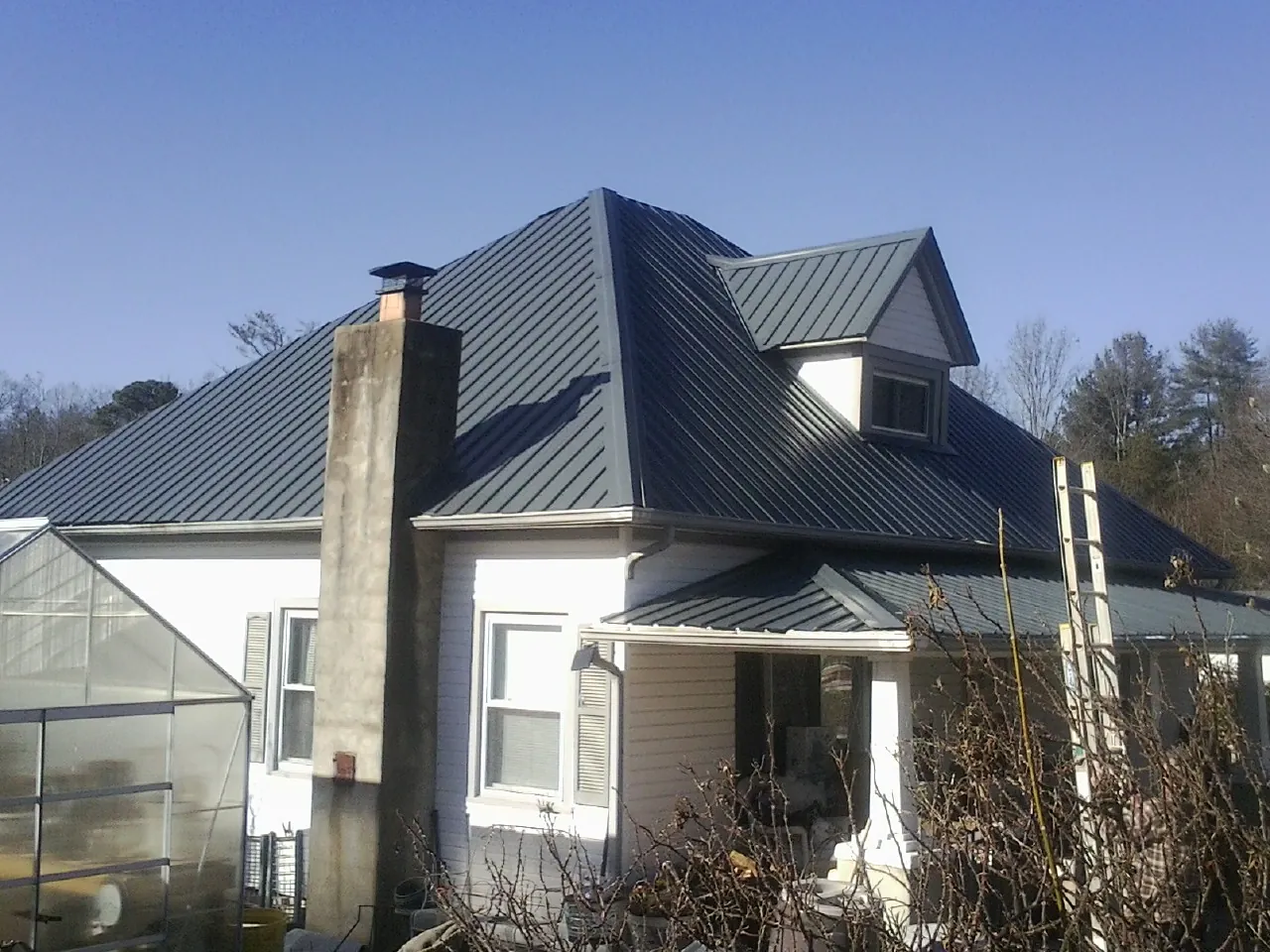 Dark blue standing seam metal roof on a white farmhouse with dormer — Slate & Tile Roof Repair by Roofing Brothers in Bellmawr