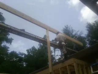 Carpenter setting a ridge beam over a new addition frame — Ice Dam Removal by Roofing Brothers in Bellmawr