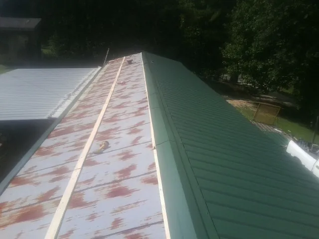 Old rusted panels beside newly installed green metal roofing — Wind Damage Roof Repair by Roofing Brothers in Bellmawr