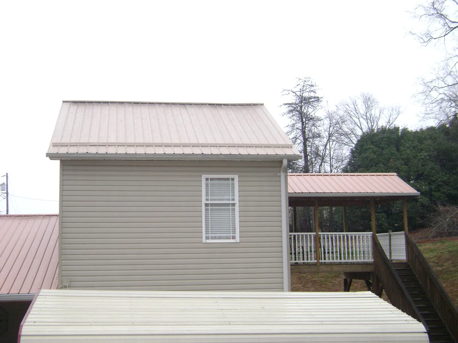 Tan metal roofs on a two story addition and attached porch, from a Roof Replacement job in Bellmawr