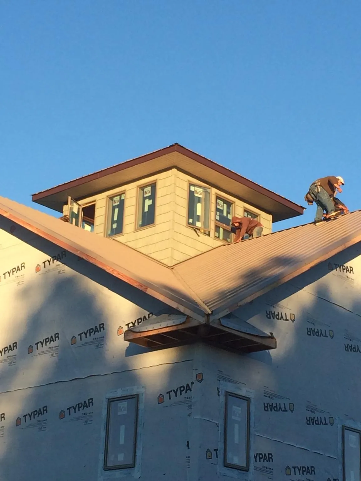 Roofers working around a rooftop cupola on a new metal roof at sunset — Roof Waterproofing in Bellmawr by Roofing Brothers